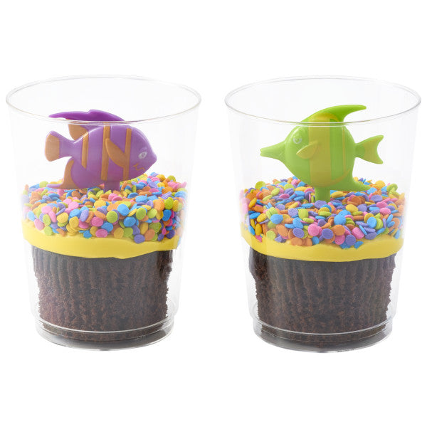 Two chocolate cupcakes in clear cups topped with yellow frosting, rainbow confetti sprinkles, and fish-shaped Sealife Friends topper picks.