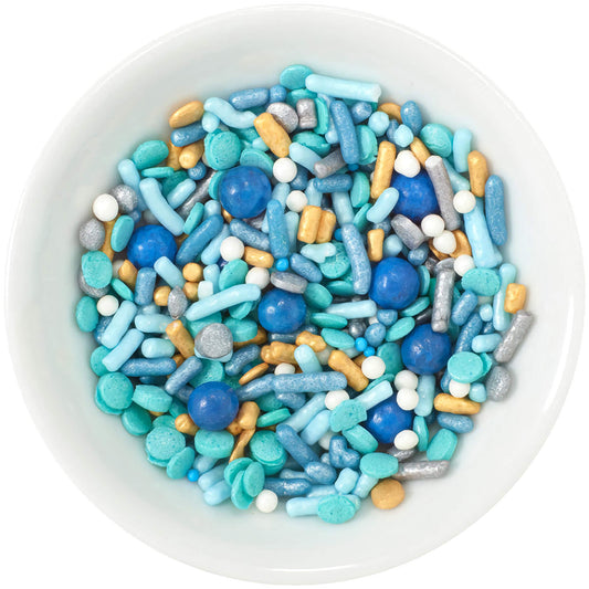 A bowl filled with Seaside Deluxe Sprinkle Blend showcasing a marine-inspired mix of various blue and gold sprinkles, including shiny beads, rods, and sugar rocks, perfect for ocean-themed desserts.