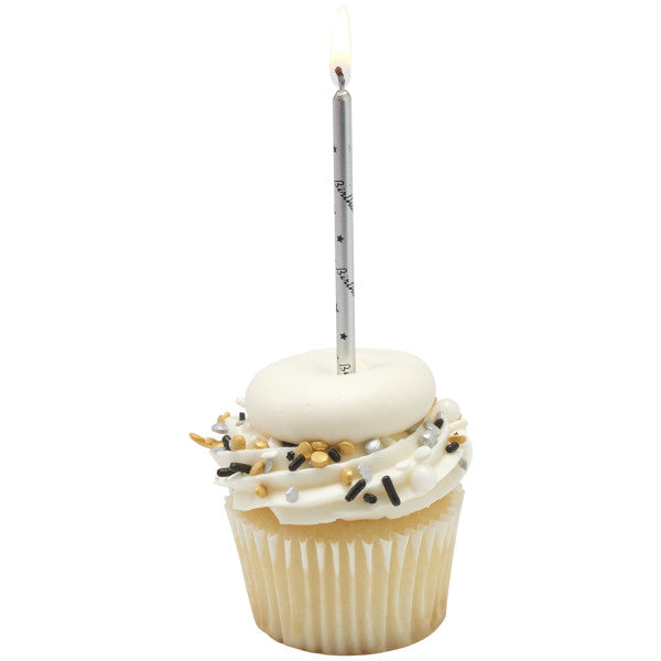Vanilla cupcake with white frosting and black, gold, and silver sprinkles, topped with a lit silver “Happy Birthday” printed candle on a white background.