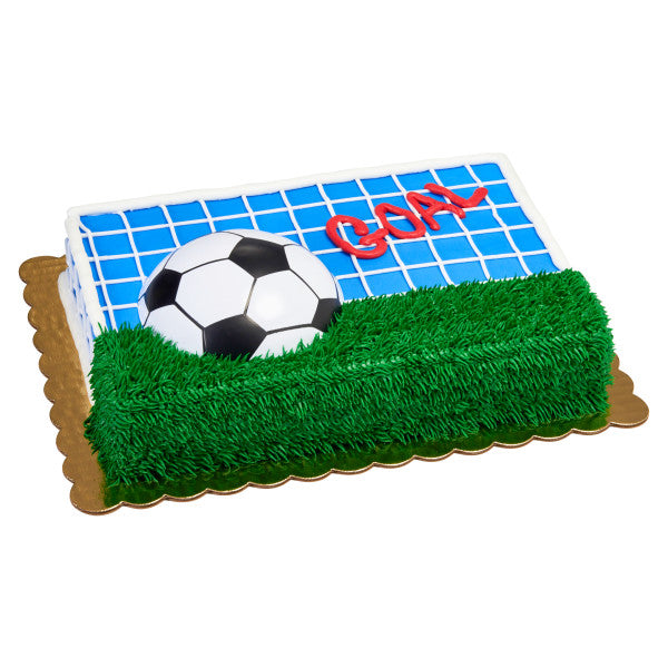 Vibrant soccer ball cake with 'GOAL!' lettering, featuring a black and white soccer ball half-embedded in green icing with grass details and a border of blue and white. Ideal for soccer fans and sports-themed parties.