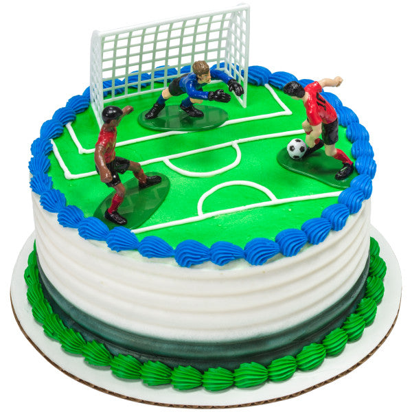 Round soccer-themed cake with white icing, green and blue trim, and three soccer player toppers on a field design.