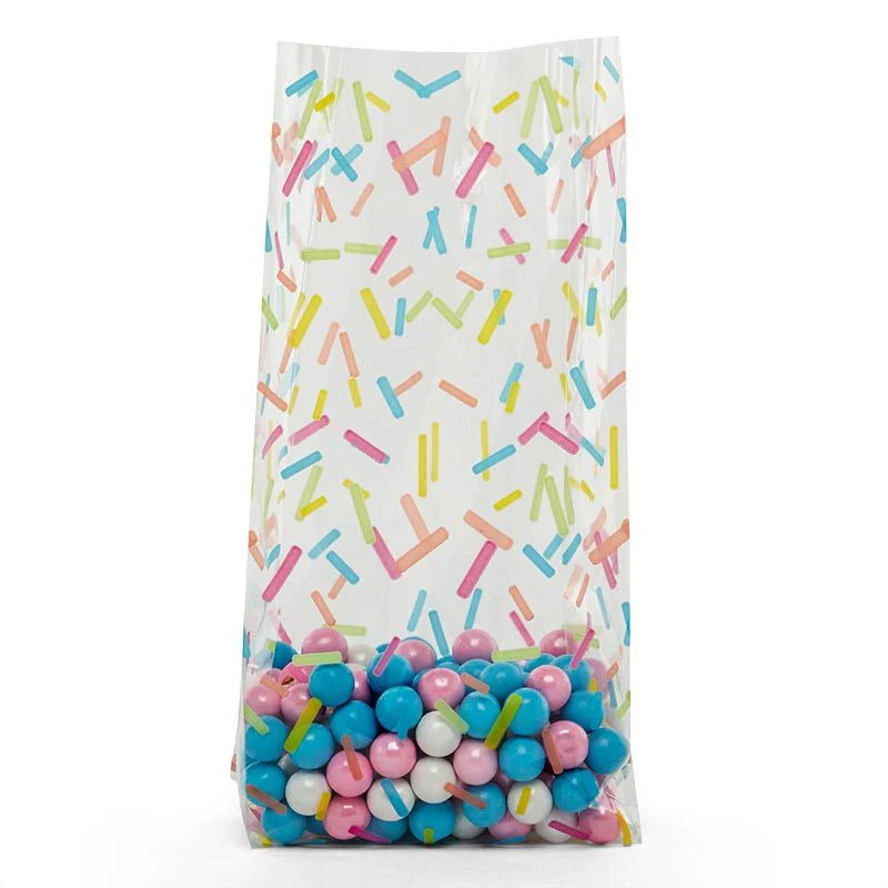 Clear cellophane treat bag with colorful sprinkle pattern, filled with blue, pink, and white candy pearls.