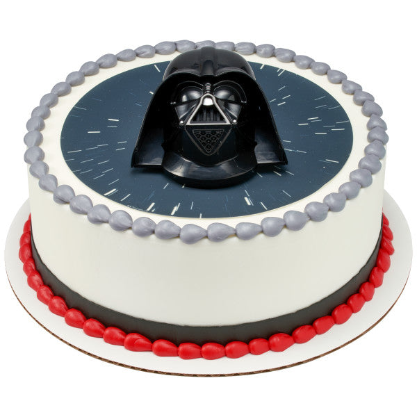 Round cake with a Star Wars space background, decorated with a Darth Vader topper and red and silver icing accents.