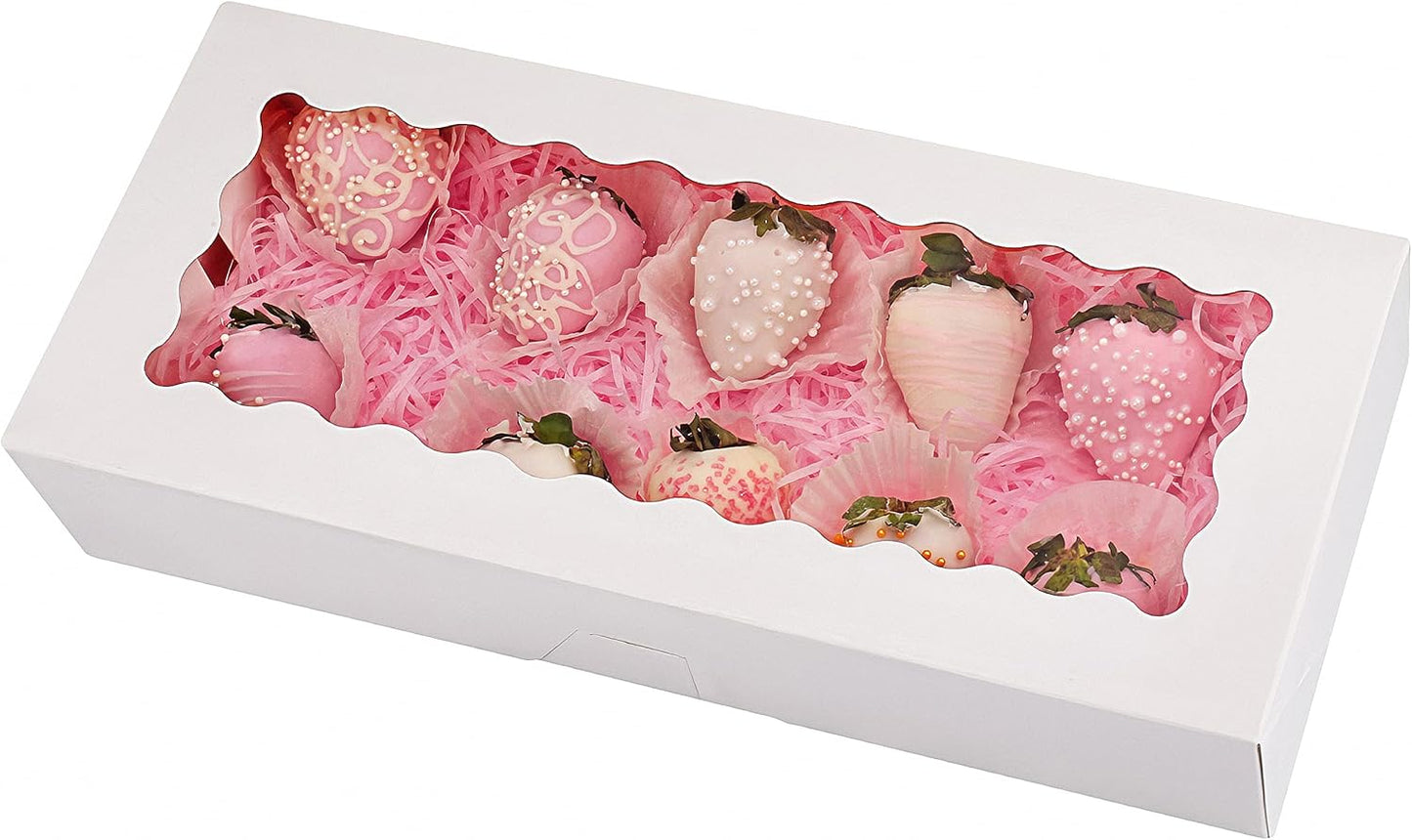 A white bakery box filled with pink and white chocolate-covered strawberries, arranged with pink decorative paper, visible through a clear window.