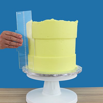 PME Latitude Ring Side Scraper in action, creating ringed patterns on a tall buttercream cake.