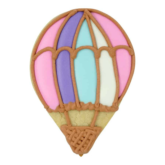 Decorated sugar cookie in the shape of a hot air balloon, featuring pastel pink, purple, and blue icing with brown piping details for basket and panels.