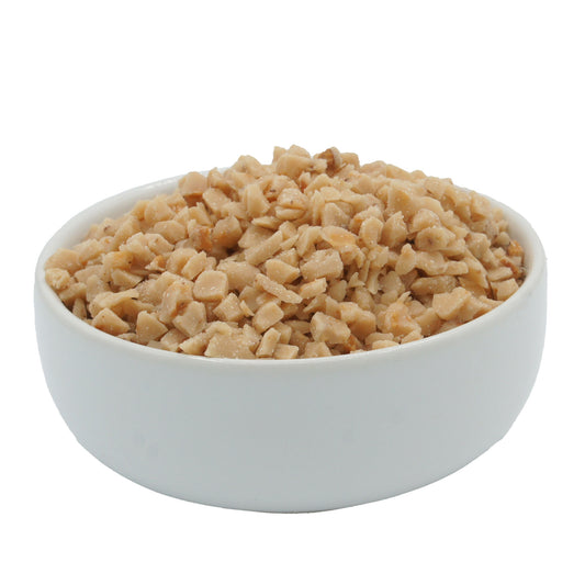 Side view of toffee candy crunch pieces in a white bowl, showing golden, bite-sized bits perfect for baking and candy making