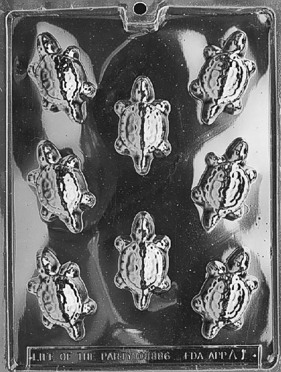 Clear candy mold with eight small sea turtle shapes, each showing a textured shell and flippers, arranged on a glossy plastic sheet against a dark background.