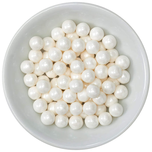 A white bowl filled with shiny, perfectly round white edible sugar pearls, each 7mm in size, ideal for elegant dessert toppings.