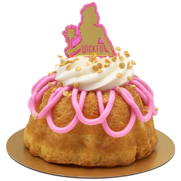 Vanilla mini bundt cake with pink drizzle and white frosting swirl, topped with a pink Wicked pick featuring Glinda’s silhouette.