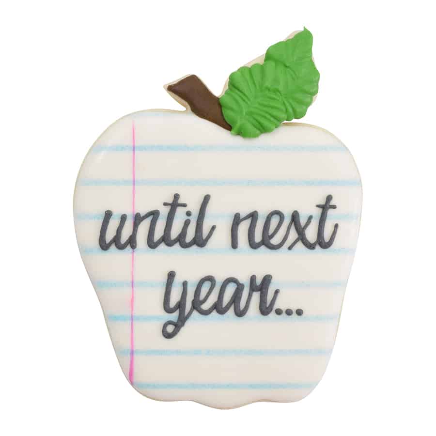 Decorated apple-shaped sugar cookie with a white icing base and blue notebook lines, featuring the words “until next year...” in script.