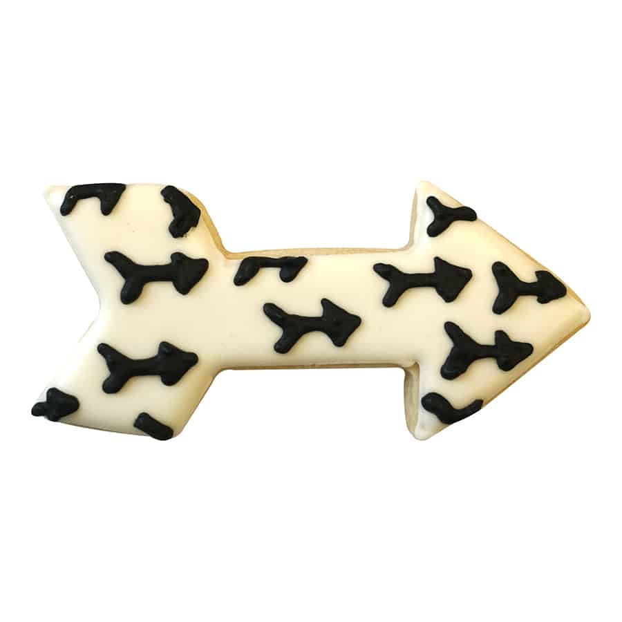 Decorated arrow-shaped sugar cookie with white icing and black arrow patterns.
