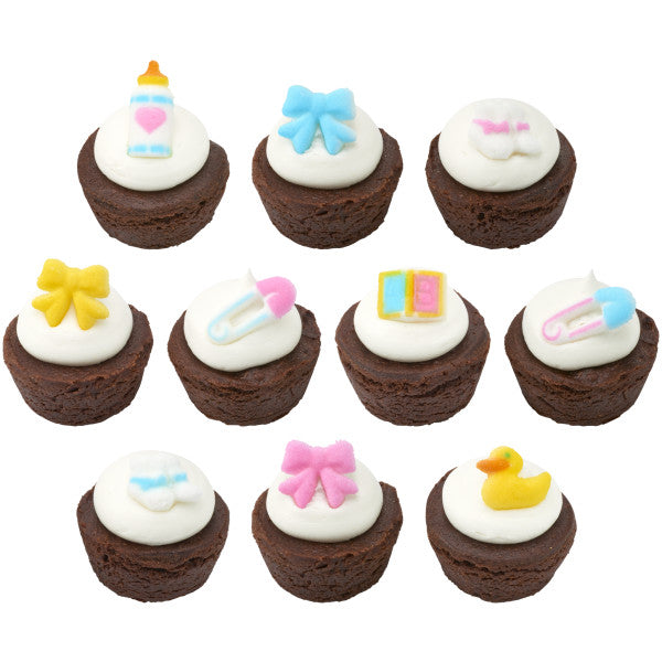 Chocolate mini cupcakes decorated with baby-themed sugar toppers including rubber duckies, bottles, pins, bows, and booties.