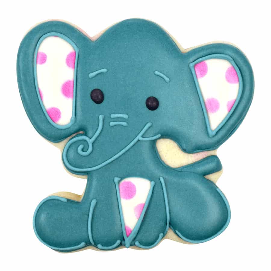 A decorated baby elephant cookie with teal icing, pink polka-dotted ears, black eyes, and a curled trunk.
