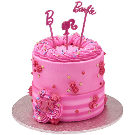Pink Barbie birthday cake topped with glitter “B,” Barbie script, and ponytail silhouette cupcake picks
