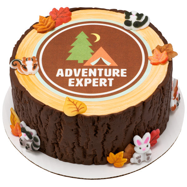 Round cake with printed “Adventure Expert” topper and bark-textured sides