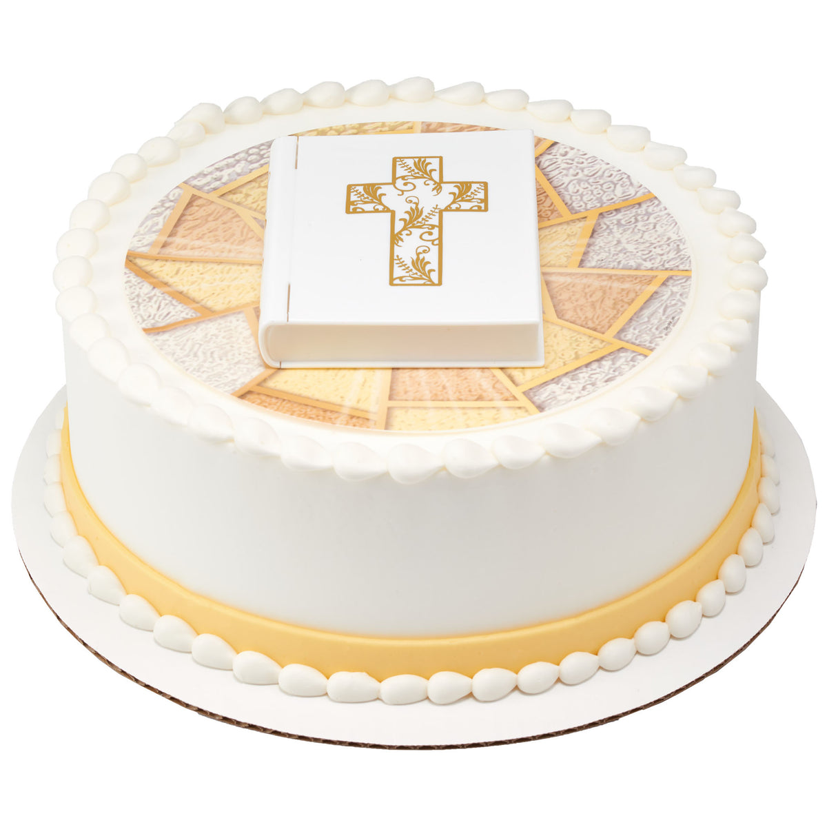 White Bible cake topper displayed on a round religious celebration cake with a gold-and-ivory edible image and white icing borders.