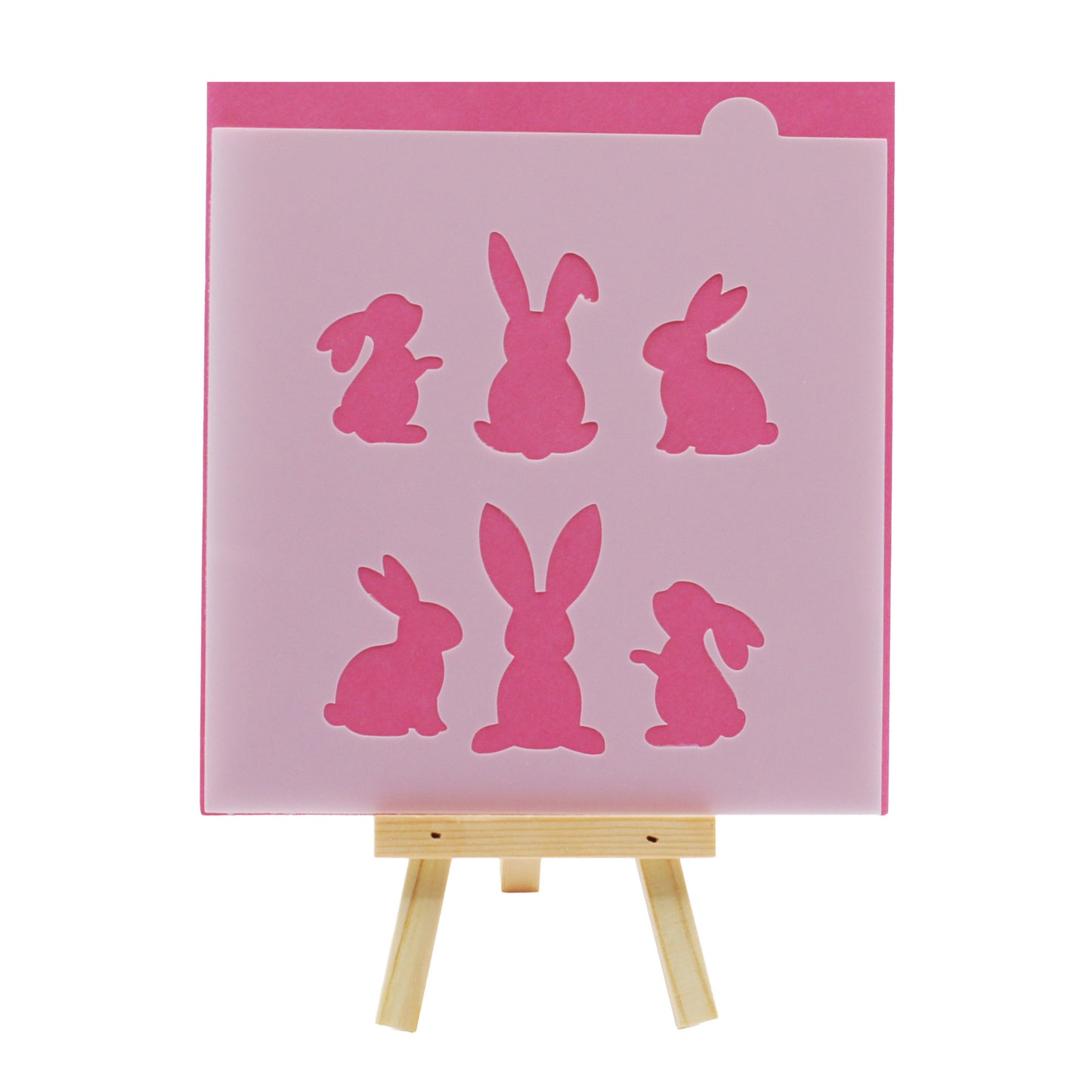 Big bunny cookie and cake stencil with six large rabbit silhouettes in different sitting poses, displayed in translucent plastic against a pink background on a small wooden easel.