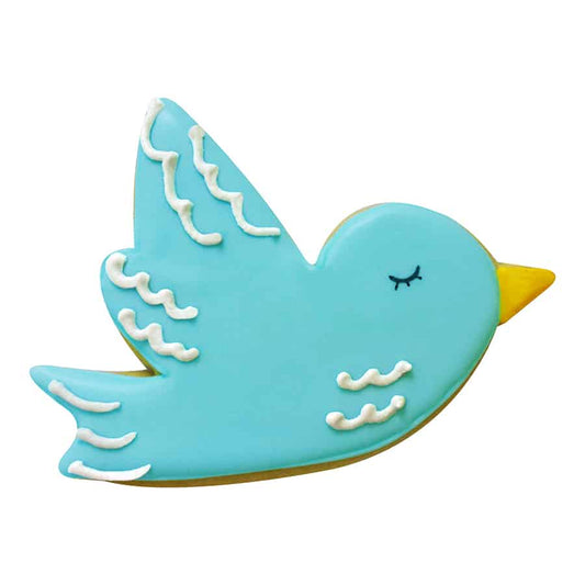 Decorated bird-shaped cookie with blue icing, white wing details, and a yellow beak.