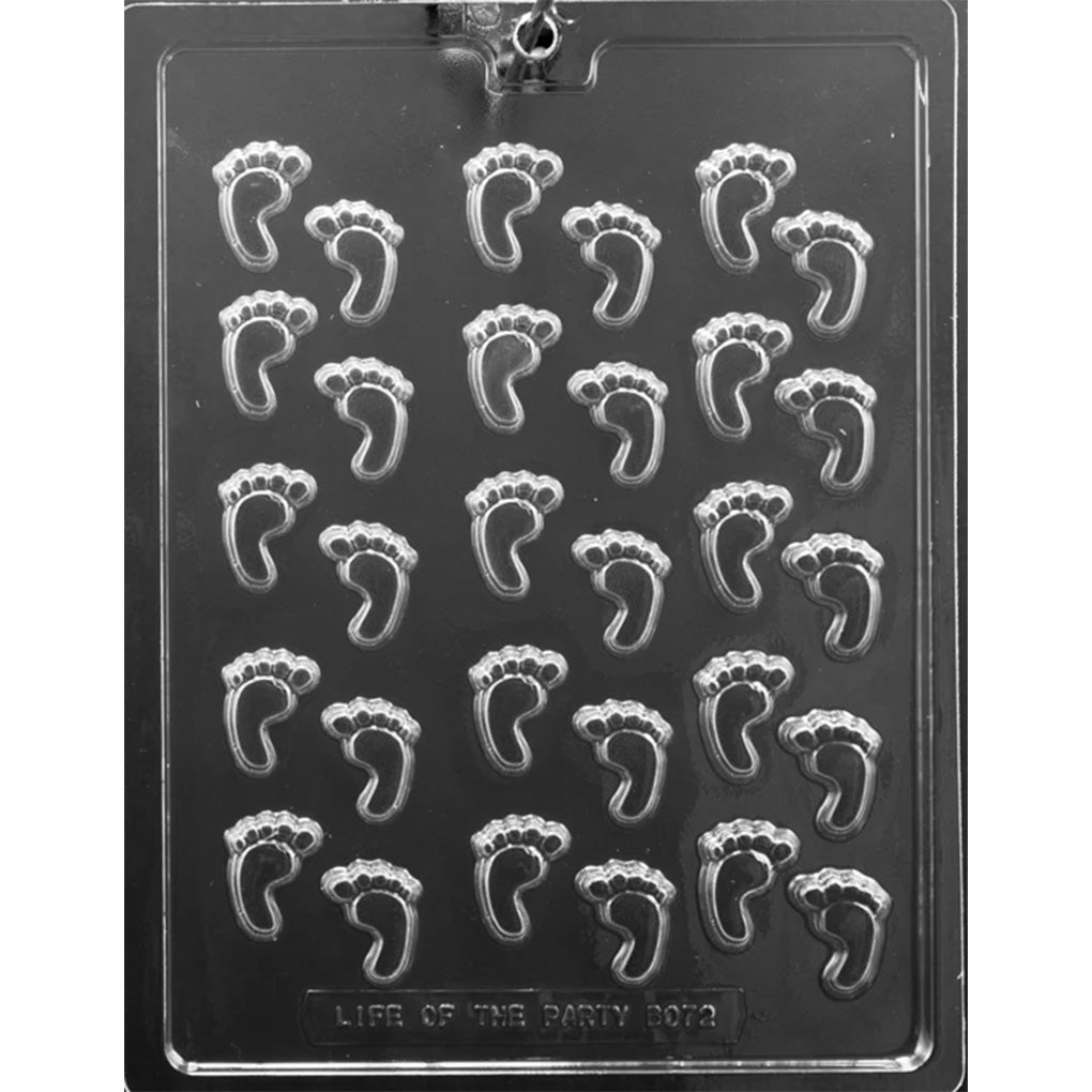 Clear plastic chocolate mold photographed on a black background with many small baby footprint cavities arranged in rows, each showing tiny toes and a curved arch.