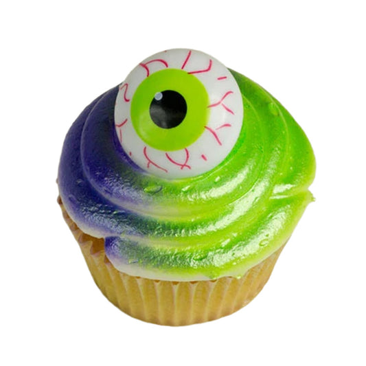 Green and purple frosted cupcake topped with a spooky green eyeball decoration for Halloween.