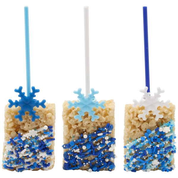 Rice Krispies treats on sticks decorated with blue sprinkles and topped with assorted snowflake rings in white, light blue, and dark blue.