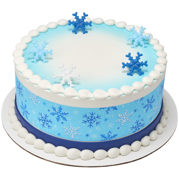 Round frosted cake decorated with blue and white snowflake rings and a matching snowflake pattern cake wrap.