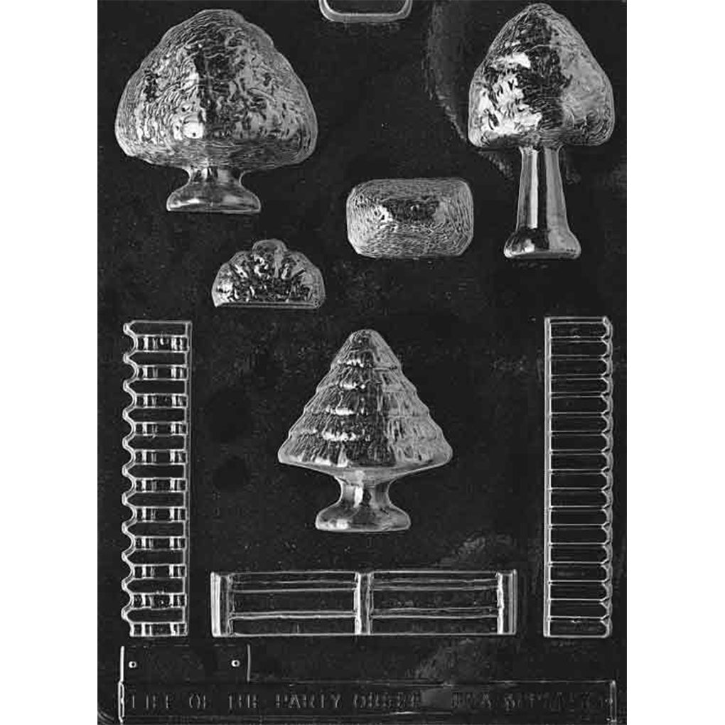 Clear plastic chocolate mold for village accessories with cavities for trees, shrubs, and fence sections used to decorate an edible chocolate village.