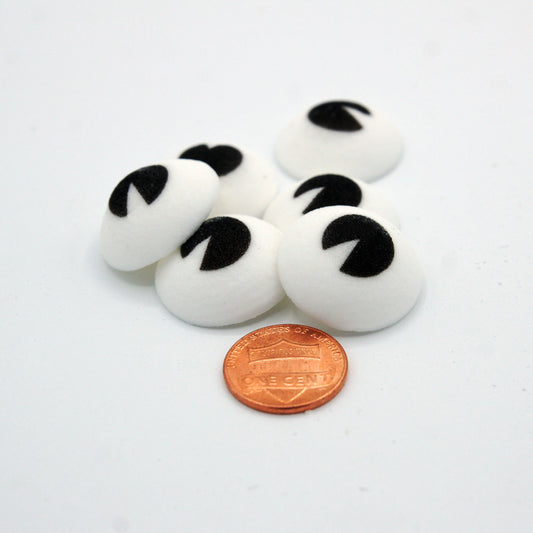 A small pile of jumbo 1" edible candy eyes next to a penny for scale, perfect for bold character-themed baked goods.