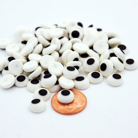 A pile of 3/8" edible candy eyes made of royal icing next to a penny for size reference — ideal for decorating cookies, cupcakes, and cake pops.