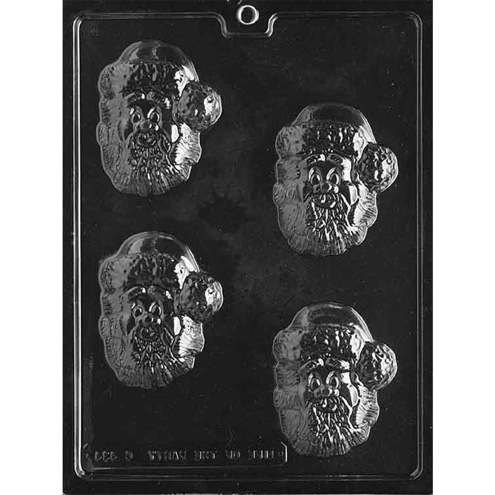 Clear plastic chocolate mold with four cartoon Santa face cavities, each showing a Santa hat with pom-pom, wide eyes, and a textured beard; shown on a dark background.