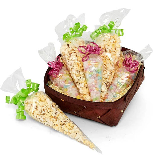 A woven basket filled with clear 12-inch cone treat bags, packed with popcorn and rainbow candy, tied with pink and green curling ribbon for festive presentation.