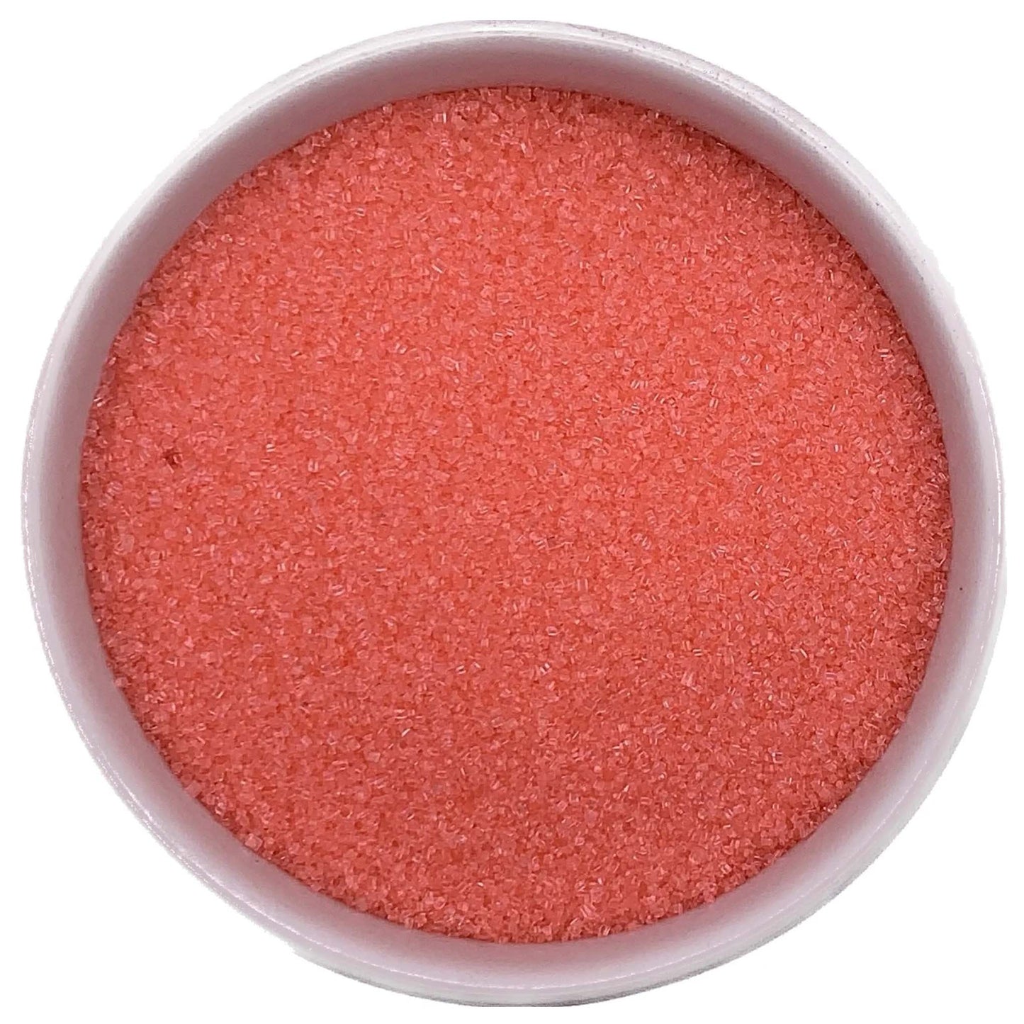 Top-down view of a white bowl filled with coral fine sanding sugar, showing tiny sparkling crystals in a soft orange-pink shade.