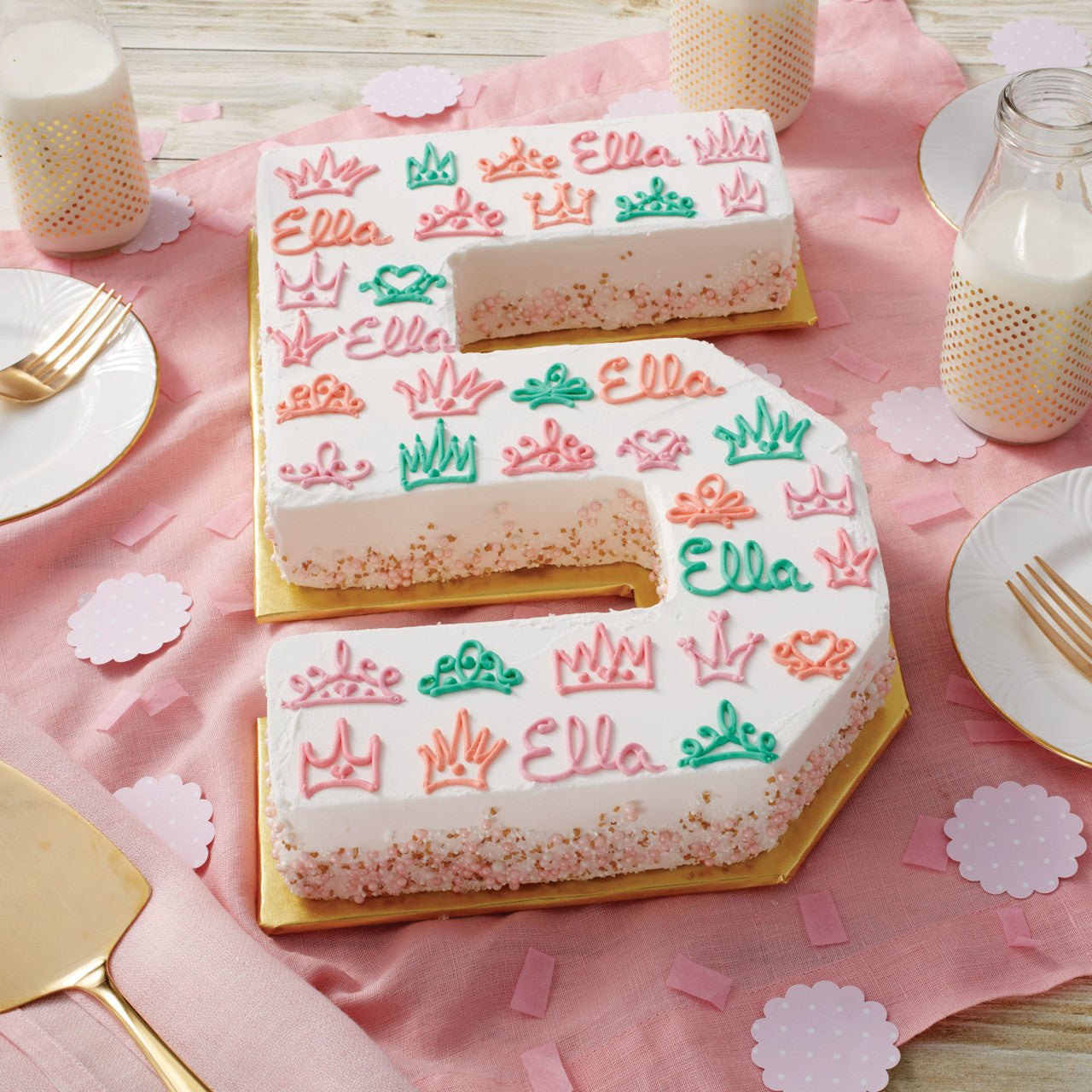 Decorated number 5 cake on a pink table setup, personalized with the name “Ella” and colorful crown piping designs.