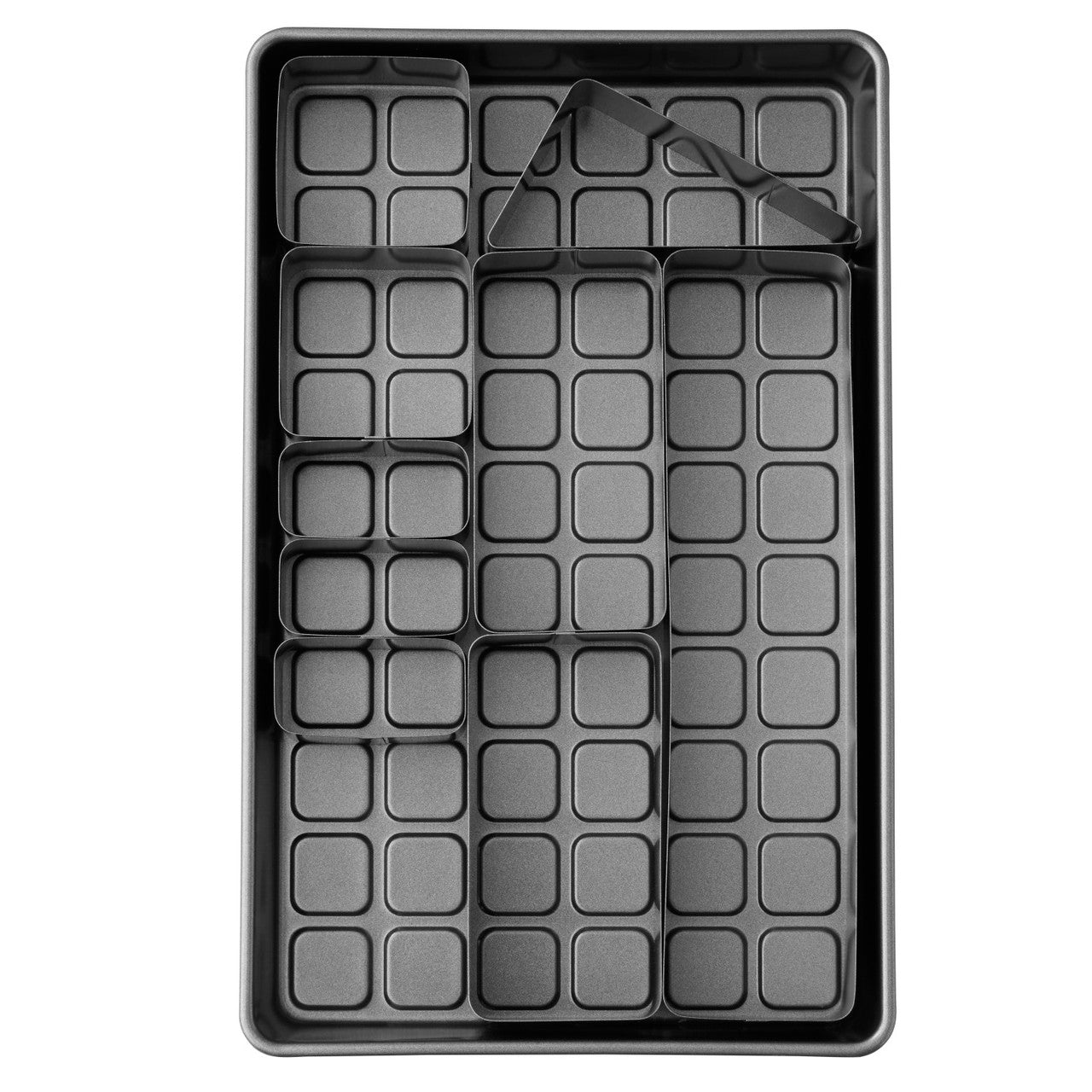Top-down view of cake pan with metal inserts in place over a gridded base, set for baking letter or number cakes.
