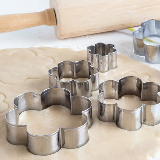 Daisy-shaped cookie cutters cutting floral shapes from rolled-out dough on a floured surface.