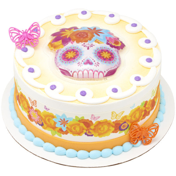 Día de los Muertos-themed cake featuring a colorful skull cake topper, floral designs, and vibrant butterfly decorations.