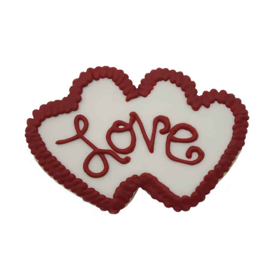 Double heart-shaped cookie with white icing and red piped "love" lettering, framed by a red icing border.