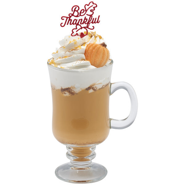 Fall-themed latte topped with whipped cream, cinnamon, and a shimmer pumpkin pressed sugar decoration.
