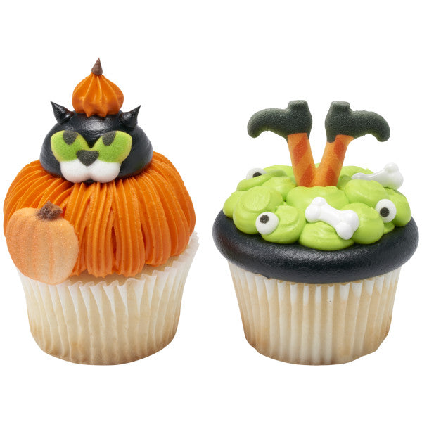 Close-up of two decorated cupcakes—one with a black cat in a pumpkin design, the other with green "witch cauldron" frosting, both topped with shimmer pumpkin sugar accents.