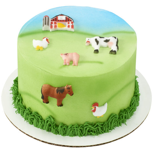 Green frosted cake topped with farm-themed sugar decorations including a red barn, cows, chickens, pig, and horse, arranged in a playful barnyard design.