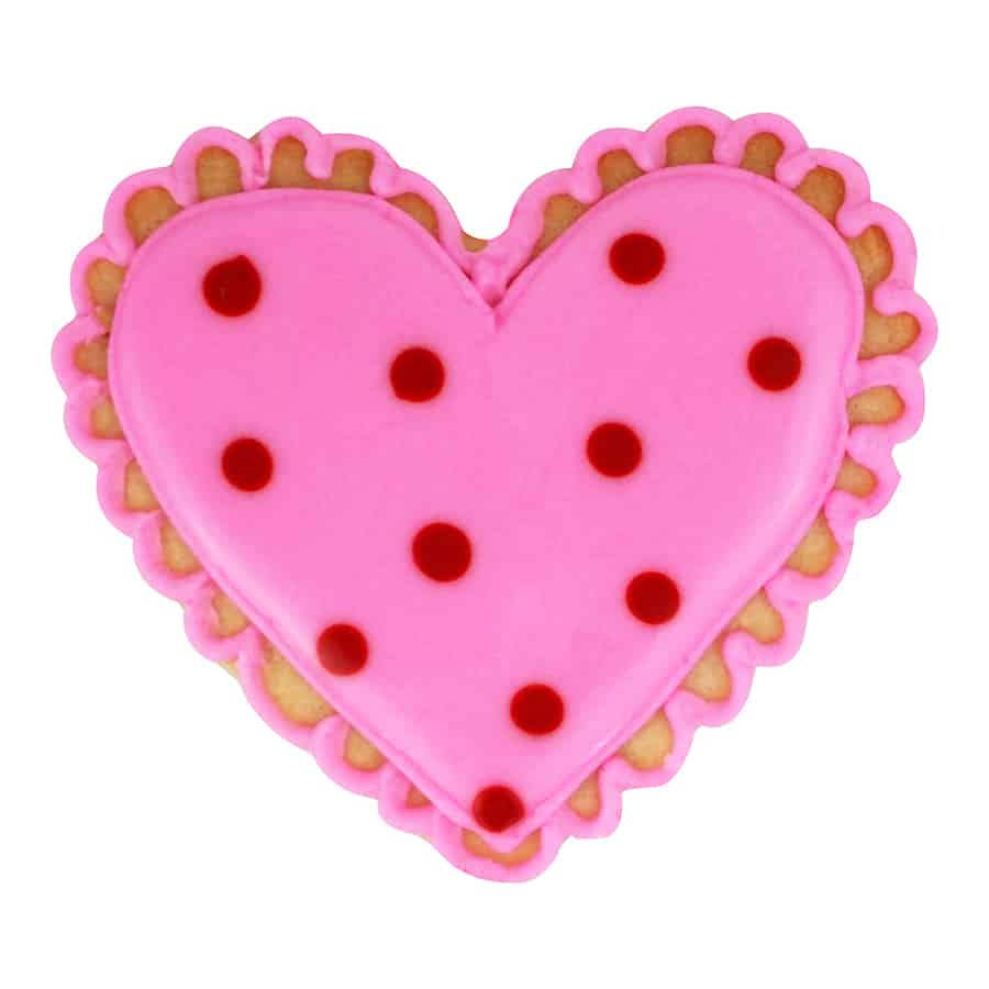 Pink heart cookie with red polka dots and a scalloped icing border, cut with a fluted heart cookie cutter.