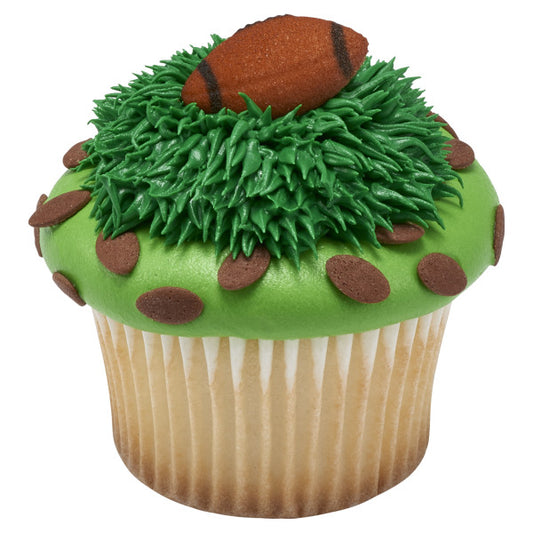 Cupcake decorated with green frosting piped to resemble turf, topped with a brown sugar football decoration and chocolate dot accents around the edge.