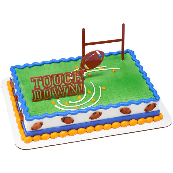 Sheet cake decorated as a football field with green icing, goalpost and "Touchdown!" pick, and a border of brown pressed sugar football decorations along the sides.