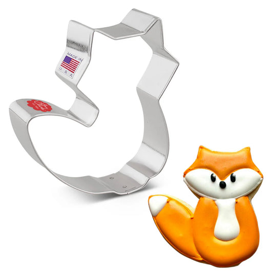 Fox cookie cutter alongside a decorated orange and white fox-shaped cookie.