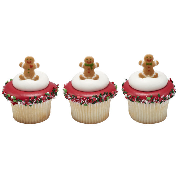 Three holiday cupcakes with red icing, white frosting domes, and pressed sugar gingerbread men on top, finished with festive sprinkles around the edges.