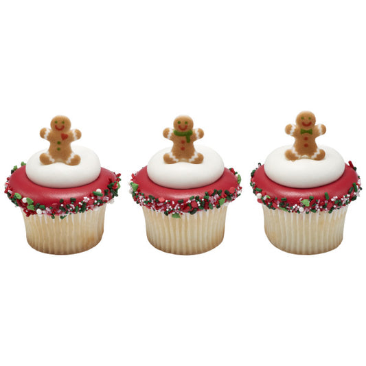 Three holiday cupcakes with red icing, white frosting domes, and pressed sugar gingerbread men on top, finished with festive sprinkles around the edges.