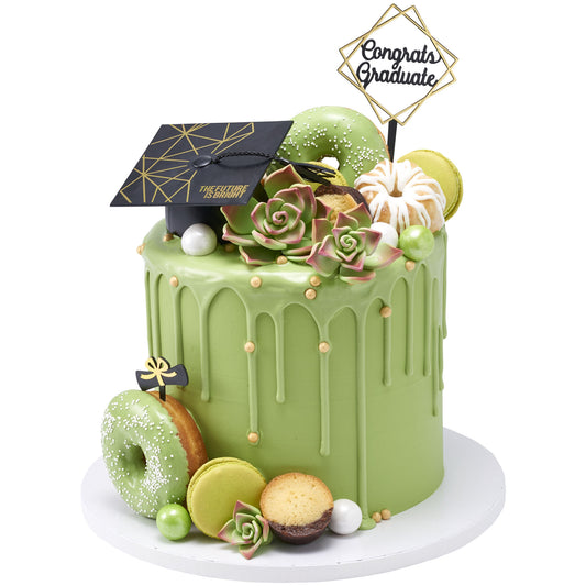 Green drip graduation cake decorated with a black-and-gold cap layon, Congrats Graduate pick, and diploma pick