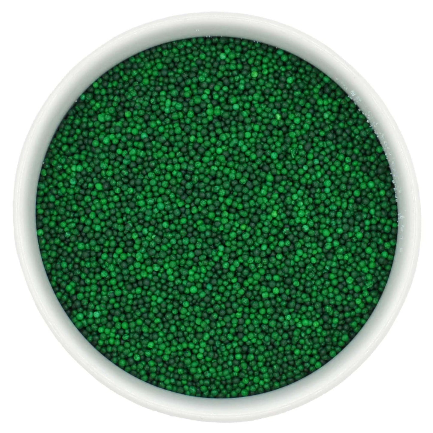 Top-down view of a white bowl filled with green non-pareils, showing tiny round sprinkle beads in mixed shades of bright and deep green.