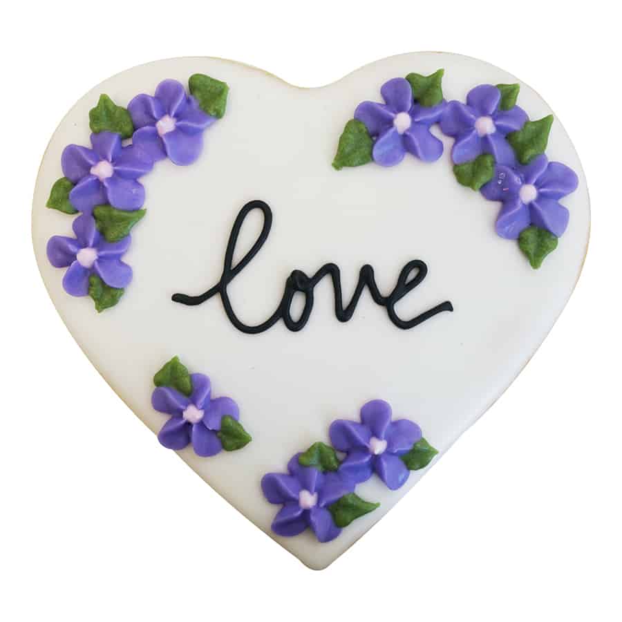 Heart cookie with piped purple flowers and the word "love" in black icing